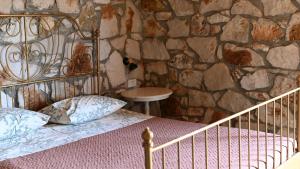 a bedroom with a bed and a stone wall at Filoxenia - The Place of Experience in Himare
