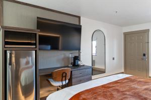 a bedroom with a bed and a kitchen with a refrigerator at Zion Promenade Hotel in St. George