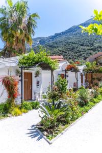 a white house with flowers and plants in front of it at Sunmed Lodge in Oludeniz