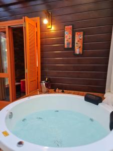 a jacuzzi tub in a room with a wooden wall at Chalés Serras House Casa Verde e Casa Laranja in São Francisco de Paula