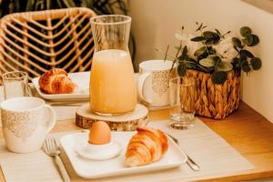 a table with a breakfast of croissants and an orange juice at Sable & Pampas - Meublé de Tourisme 5 étoiles - Vue Panoramique & Terrasse - Climatisation - Plage à 200m in Carnon-Plage