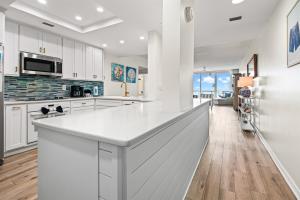 a kitchen with white cabinets and a large white island at Modern Gulf Front Condo, Pool, 2 Hot Tubs, Platinum Beach Service, Endless Views in Navarre