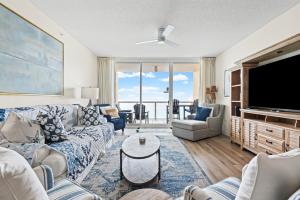 a living room with a couch and a flat screen tv at Modern Gulf Front Condo, Pool, 2 Hot Tubs, Platinum Beach Service, Endless Views in Navarre
