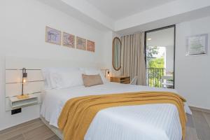a bedroom with a white bed with a yellow blanket on it at Bit Building in Medellín