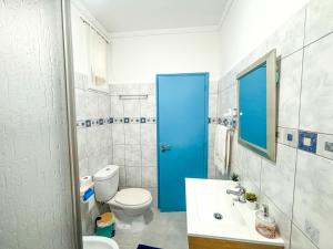 a bathroom with a toilet and a blue door at Casa da Pedra in Moledo