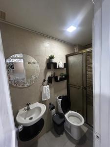 a bathroom with a sink and a toilet and a mirror at Apartamento amoblado Chinchina in Chinchiná