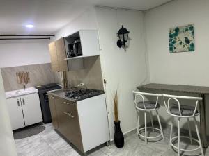a small kitchen with a stove and two stools at Apartamento amoblado Chinchina in Chinchiná