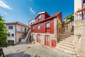 a red building with red doors on a street at Casa da Obrinha in Bouro