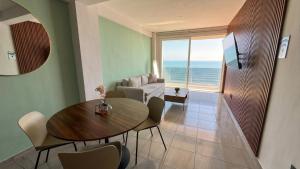 a living room with a dining table and a view of the ocean at Grandeza by Palms Boca del Río in Boca del Río