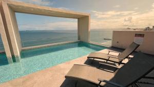 a swimming pool with chairs and a view of the ocean at Grandeza by Palms Boca del Río in Boca del Río