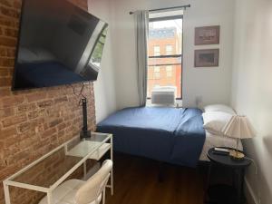 a small bedroom with a blue bed and a window at The Revival Guest House near Times Square in New York
