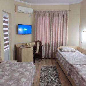 a hotel room with two beds and a desk and a tv at Hotel Fantasy in Lyubimets +65 photos