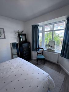 a bedroom with a bed and a window and a chair at Palm Valley Villa in Poole