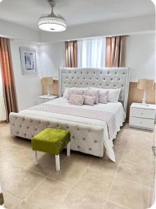 a white bedroom with a large bed with a green stool at Franco Residence in Santiago de los Caballeros