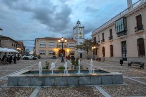 a fountain in front of a building with a clock tower at Apartamento manchego Macrina in Villarta de San Juan