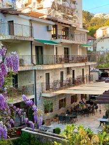 a building with tables and chairs and purple flowers at Apartments Amber House in Topla