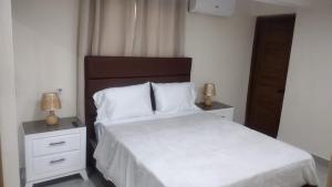 a bedroom with a white bed with two nightstands and two lamps at Johanna 1 in Los Tres Ojos de Agua