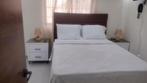 a bedroom with a large bed with white sheets and pillows at Johanna 1 in Los Tres Ojos de Agua
