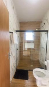 a bathroom with a toilet and a glass shower at Recanto da Nonô in Gonçalves +22 photos