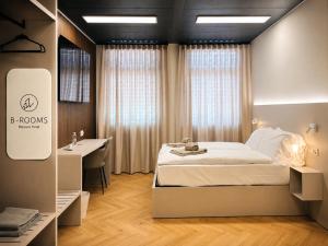 a bedroom with a bed and a desk and a sink at B-ROOMS Bleisure Hotel - Lugano district in Manno