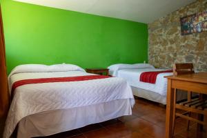two beds in a room with green walls at Hotel Posada La Ermita Cobán in Cobán