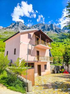 a large house with a balcony and mountains in the background at Arditis Cozy Studio in Bogë