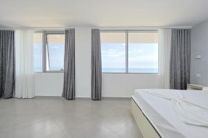 a bedroom with two windows and a bed with white sheets at Luxury sea view duplex in Durrës