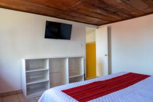a bedroom with a bed and a tv on the wall at Hotel Posada La Ermita Cobán in Cobán