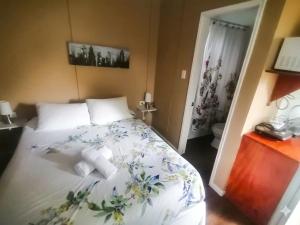 a bedroom with a white bed with flowers on it at Borde Lago IV - V in Puerto Varas
