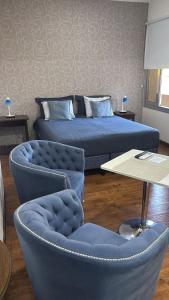 a bedroom with a bed and two chairs and a table at Departamento BLUE in San Juan