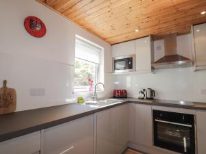 a kitchen with white cabinets and a wooden ceiling at Tigh a Phailean in Letterfearn