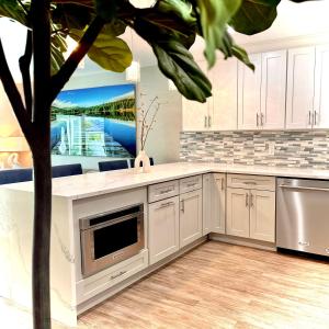 a kitchen with white cabinets and a tv and a tree at Acqua Atelier by Vanderbilt Beach in Naples