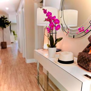 a table with a mirror and a vase with flowers on it at Acqua Atelier by Vanderbilt Beach in Naples