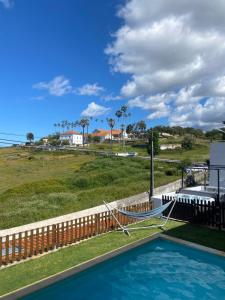 a swimming pool next to a fence and a field at Like a Local Guest House in Ericeira