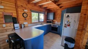 a kitchen with blue cabinets and a white refrigerator at 19 Torquay Terrace in Hanmer Springs