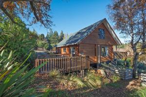 a log cabin with a fence in front of it at 19 Torquay Terrace in Hanmer Springs