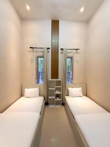 two beds in a room with two windows at Tafufu Villa Tumpak Sewu in Sumberbopong