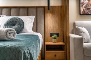 a bedroom with a bed with a pillow and a chair at Helena's Aether Suites - Seaview & Heated Infinity Pool in Tragaki +67 photos