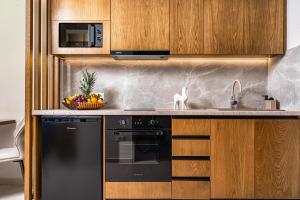 a kitchen with a black dishwasher and a sink at Helena's Aether Suites - Seaview & Heated Infinity Pool in Tragaki