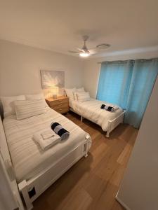 two beds in a room with blue curtains at Pet Friendly - Plunge Pool Canal Sunset View - Private Jetty in Bongaree +8 photos