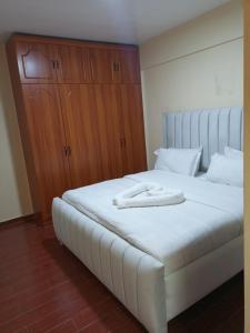 a bedroom with a large white bed with a wooden cabinet at Kaisa garden in Nairobi