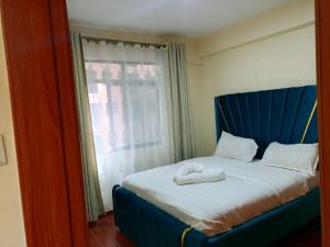 a bed with a blue headboard and a window at Kaisa garden in Nairobi