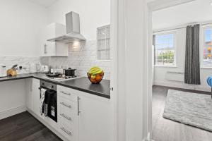 a white kitchen with a bowl of fruit on the counter at Cheshire Dimond one bedroom flat in Warrington in Warrington
