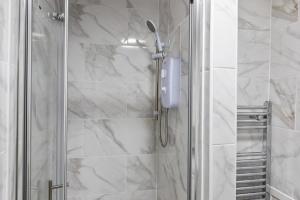 a shower in a bathroom with white marble walls at Cheshire Dimond one bedroom flat in Warrington in Warrington