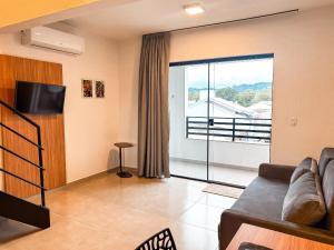 a living room with a couch and a large window at Loft Novo e Completo no Centro • 4 Pessoas in Brusque