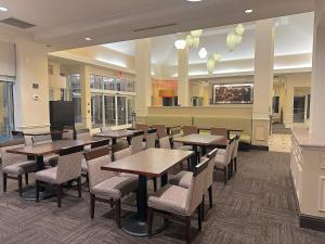 a restaurant with tables and chairs and a tv at Arnot Grand Hotel & Suites in Horseheads