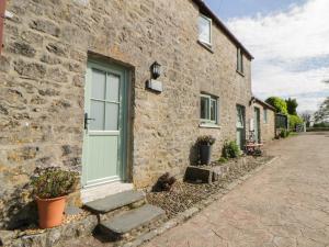 a stone building with a green door and stairs at Swallows Retreat in Kilgetty