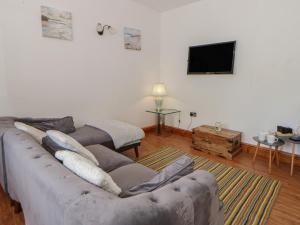 a living room with a couch and a flat screen tv at Swallows Retreat in Kilgetty