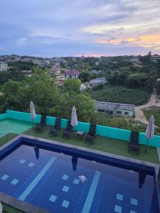 a view of a pool with chairs and umbrellas at Cape Coast Travellers' Inn in Cape Coast