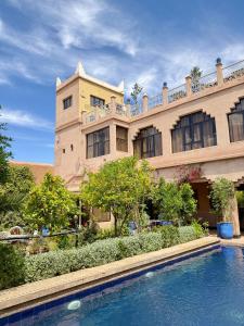 a large building with a swimming pool in front of it at Riad Tama & SPA - Authentic Ourzazate Stay in Ouarzazate
